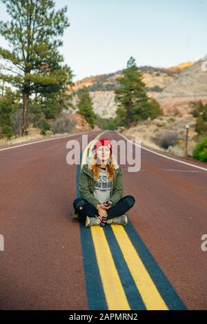 Ragazza seduto sulla strada nel Zion National Park nello Utah sudoccidentale vicino alla città di Springdale Foto Stock