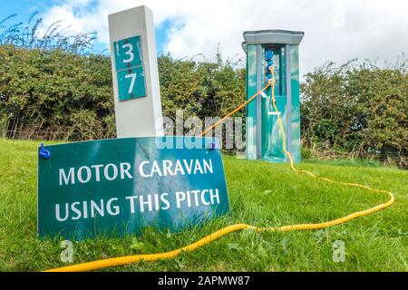 Caravan a motore con questo passo. Firmare un numero di piazzola del campeggio, con il cavo elettrico che corre da un palo di alimentazione sul retro. Inghilterra, Regno Unito. Foto Stock