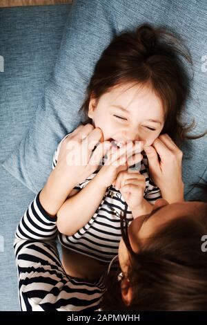 Adorabile bambina di 4-5 anni che si diverte con la sua mamma e sorridente, vista dall'alto. Infanzia felice. Foto Stock