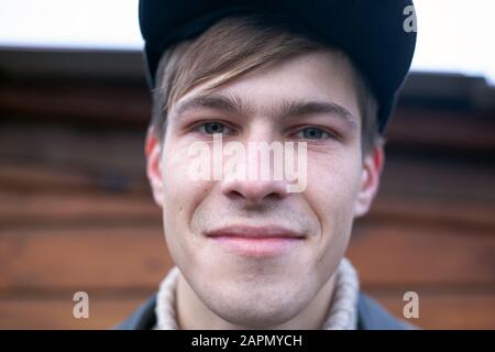 un ragazzo in un cappuccio 21-23 anni modello guarda sorridendo la fotocamera, ritratto closeup. Foto Stock