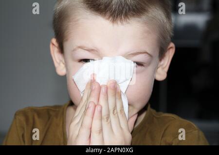 Mosca, FR, 01.26.2019: Il ragazzo pulisce il naso con un tovagliolo. Il bambino soffia il naso. Il capretto è malato con sintomi di allergia. Giovane ragazzo carino soffia hi Foto Stock