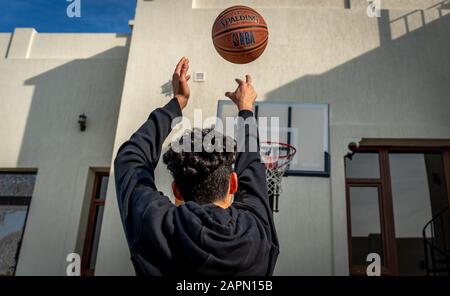 Giovane uomo che gioca a basket all'aperto nel cortile | sparare una palla al bordo | immagine naturale Foto Stock