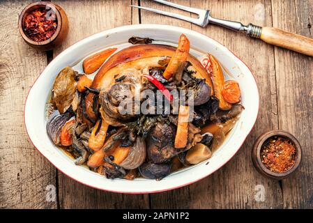 Stinco di maiale arrosto eisbein con verdure su sfondo di legno. Stanghetta di maiale brasata Foto Stock