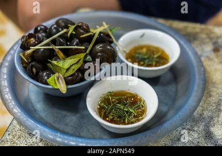 Fuoco selettivo di lumache commestibili e una salsa liquida con erbe su sfondo sfocato Foto Stock