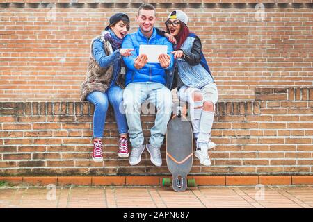 Tre amici che si divertono con il tablet all'aperto - giovani che guardano video sorpresi - tecnologia dipendenza concetto - Soft focus sulla ragazza giusta - Soft Foto Stock