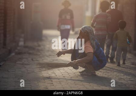 Mathura, INDIA - Febbraio 23,2018: Una donna indiana con una scopa che pulisce i locali della strada nella sua casa, Mathura, India. Foto Stock