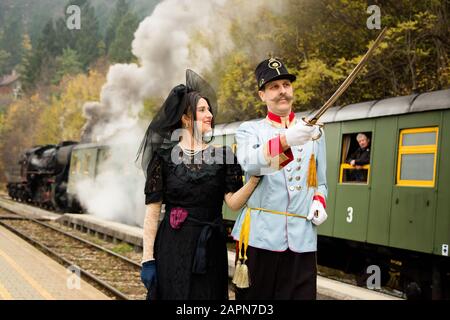 Bled, Slovenia, 4 novembre 2017: Gli attori che suonano l'arciduca austriaco Franz Ferdinand e la sua scorta posano per una fotografia di fronte a un treno museo di cento anni in attesa alla stazione ferroviaria di Bled prima di partire sulla linea ferroviaria di Bohinj (Transalpina). La linea fu costruita tra il 1900 e il 1906 come il più breve collegamento tra l'Impero Austro-Ungarico e il Mare Adriatico di Trieste (Italia). Fu inaugurato nel 1906 dall'arciduca Francesco Ferdinando. La rievocazione dell'evento è ora parte di un tour in treno. Foto Stock