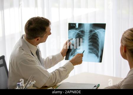 Medico che spiega i polmoni raggi X alle donne che sono pazienti in clinica o medico in ufficio che esaminano una radiografia e discutono con un paziente Foto Stock