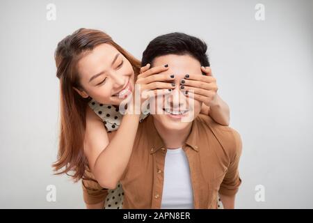 Positivo allegro donna chiudere coprire il suo coniuge uomo occhi abbraccio abbraccio piggy-back godere San Valentino celebrazione isolato su sfondo bianco Foto Stock