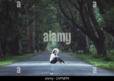 Donna seduta nella strada profonda foresta Foto Stock