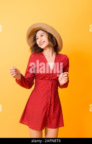 Ragazza asiatica indossando abito rosso con cappello di paglia su sfondo arancione Foto Stock