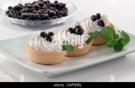 Pasticcini fatti in casa con crema di formaggio e frutti di bosco freschi - uve secche di Corinto e le foglie di menta Foto Stock