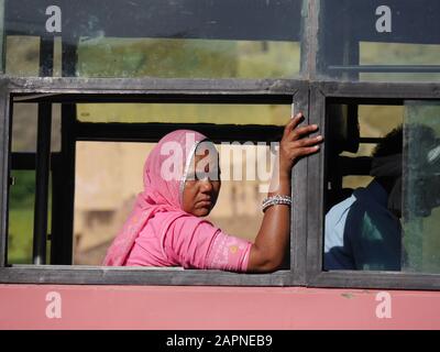 Donna indiana in sari che guarda pensieroso fuori dalla finestra dell'autobus Foto Stock