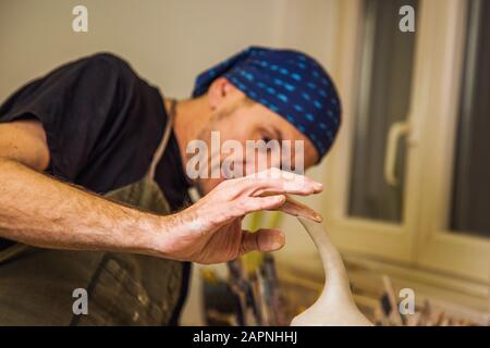 Vasaio maschio in studio finitura dettaglio opere su nuova anfora, poco profondo debito di campo, mani fuoco Foto Stock