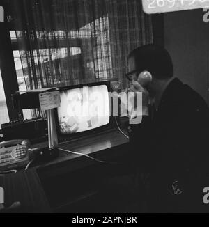 Circuito TV chiuso per la sicurezza nelle sale stampa e conferenze di Schiphol Un dipendente al telefono dietro lo schermo Data: 3 gennaio 1974 Località: Noord-Holland, Schiphol Parole Chiave: Sicurezza, schermi televisivi Foto Stock