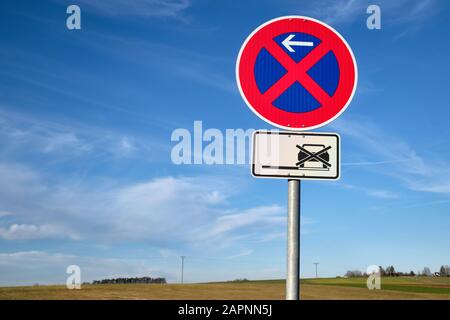 Il segnale del traffico rosso e blu davanti al bel cielo blu e al paesaggio di campagna dice assolutamente nessuna fermata qui anche sulle spalle dure. Vista in Foto Stock