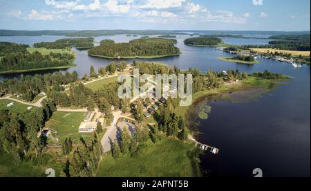 Vista aerea del lago blu e delle foreste verdi in una soleggiata giornata estiva sopra un campeggio caravan. Fotografia con drone con vista dall'alto. Ruovesi, Finlandia. Foto Stock