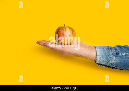 Uomo che tiene in mano una mela rossa su sfondo giallo Foto Stock