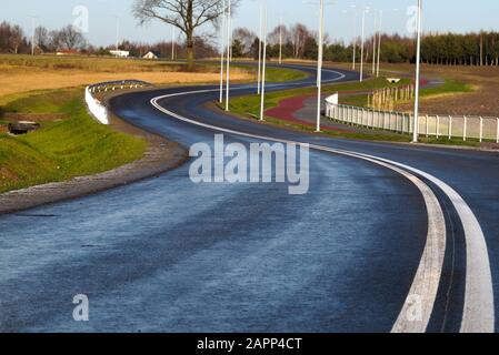 Nuove superfici, luci e percorsi ciclabili. Una strada locale di recente costruzione. Foto Stock