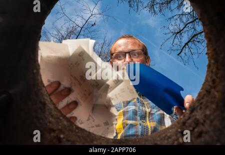 un uomo vuole sbarazzarsi delle sue ricevute in un buco nel terreno nel giardino Foto Stock