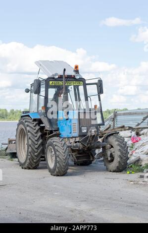 Trattore leggero bielorusso con ugello, benna e martello pneumatico, per la riparazione e la modernizzazione della strada asfaltata. Russia. Foto Stock