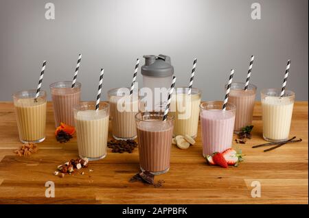 Vetri di vari tipi di frullato colorato con cannucce di carta e gli ingredienti su un tavolo di legno top Foto Stock