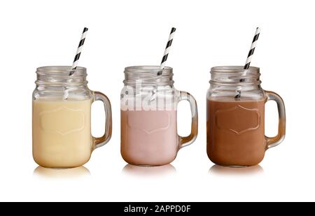 Milkshake di banana, fragola e cioccolato in bicchieri da Vasetto Mason, con cannucce di carta, isolati su uno sfondo bianco con ombra goccia Foto Stock