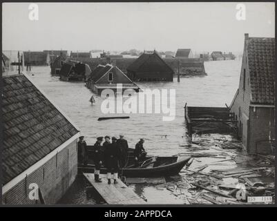 Watersnood 1953. Dopo due mesi, l'acqua in questo luogo, che è ancora completamente isolata, è ancora alta come il giorno del disastro della tempesta il 1 febbraio 1953. Solo con barca a remi può il villaggio dove sono presenti 15 persone. L'approvvigionamento idrico viene effettuato tramite nave cisterna, che viene effettuata in serbatoi sul posto. Le vittime sono ancora in fase di ricerca e, per quanto possibile, vengono ancora estratte dall'acqua, cosa che potrebbe essere ancora utile in futuro. Data: 7 aprile 1953 luogo: Nieuwerkerk, Zeeland Parole Chiave: Barche, viste del villaggio, servizi di soccorso, inondazioni Foto Stock