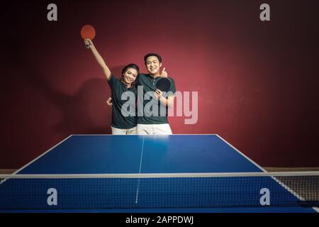 Coppie di giovani che giocano a ping pong con le pagaie da ping pong che si divertono Foto Stock