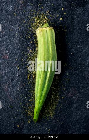 vista ad alto angolo di una capsula di okra grezza su una superficie di pietra nera Foto Stock