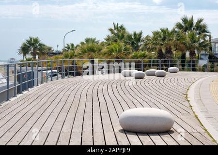 Larnaca argankment, Cipro in primavera. Vista sul lungomare di Larnaca con palme e panchine a forma di pietra, zona parco vicino alla spiaggia Foto Stock