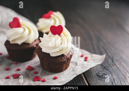 Valentino tortini, decorata con cuori dolci scuro su un tavolo di legno. Posto per il testo. Foto Stock