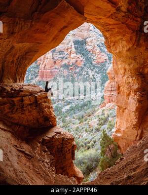 Donna seduta sul bordo della roccia nella grotta, Sedona, Arizona, Stati Uniti Foto Stock