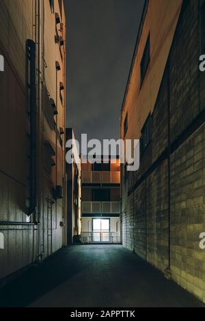 Un vicolo stretto con alti edifici a più piani su entrambi i lati di notte in Osaka, Giappone Foto Stock