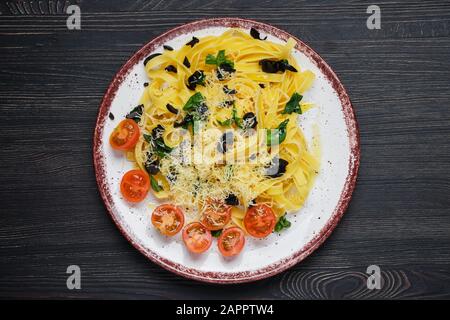 Vista dall'alto delle tagliatelle con pomodoro, parmigiano, olive tritate e basilico Foto Stock