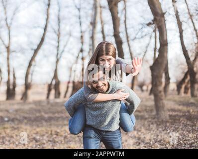 Felice giovane coppia gioiosa di divertirsi piggybacking ridere insieme in autunno Foto Stock