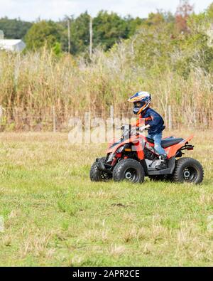 Bambino che guida un 4 ruote nel paese. Il pilota indossa un casco. Il bambino ha 6 anni. Foto Stock