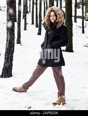 Giovane ragazza felice e bella teenage vestita di abbigliamento invernale in piedi alla neve e sorridente. Montagne Troodos a Cipro Foto Stock