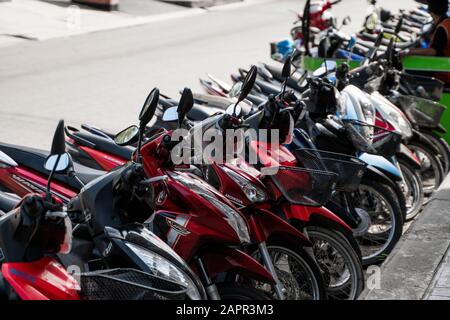 KRABI, Tailandia - 10 luglio 2019. Affollati parcheggio posto in Krabi con piena di motociclette. Un sacco di moto parcheggio nelle righe sul marciapiede in Foto Stock