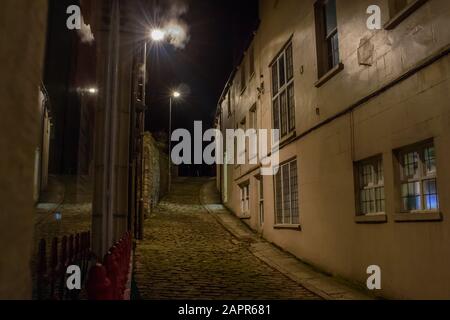 La cittadina di mare Acciottolata E Scarsamente Illuminata si torce in salita a Swanage Foto Stock