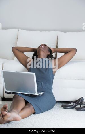 Donna di mezza età appoggiata su un divano e sorridente Foto Stock