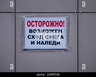 Un messaggio di carta incollato alla parete con nastro adesivo con la scritta avvertenza in russo - attenzione, neve e ghiaccio possono scendere. Mosca, Russia Foto Stock