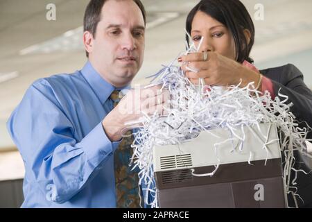 Close-up di un imprenditore e imprenditrice guardando SHREDDED PAPER Foto Stock