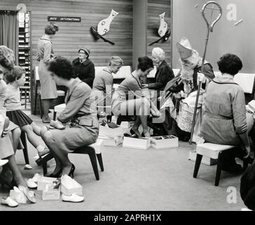 Sinterklaas in mezzo ad altri clienti e venditori che lavorano su scarpe da calzare in un negozio di scarpe Bata di Haarlem. Olanda, Haarlem, 8 Novembre 1960. Foto Stock