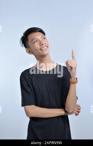Un ritratto di un giovane asiatico che ottiene un gesto di mano di idea. Puntando su per copiare lo spazio. Puntando con il dito indice una grande idea. Un'Idea Intelligente Foto Stock