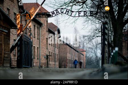 24 gennaio 2020, Polonia, Oswiecim: Nel tardo pomeriggio, i visitatori camminano attraverso la porta dell'ex campo di concentramento di Auschwitz i con l'iscrizione 'Arbeit macht frei'. 27.01.2020 ricorre il 75th anniversario della liberazione del campo di concentramento da parte dell'Armata Rossa. Dal 1940 al 1945, la SS gestiva il complesso con numerosi campi satellite come campi di concentramento e di sterminio. Il numero di coloro che sono stati uccisi ammonta a 1,1 - 1,5 milioni, la maggior parte dei quali ebrei. Auschwitz è il simbolo dell'omicidio di massa industriale e dello sterminio degli ebrei. Foto: Kay Nietfeld/Dpa Foto Stock