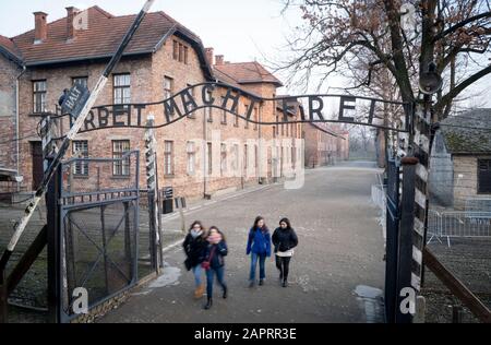 24 gennaio 2020, Polonia, Oswiecim: Nel tardo pomeriggio, i visitatori camminano attraverso la porta dell'ex campo di concentramento di Auschwitz i con l'iscrizione 'Arbeit macht frei'. 27.01.2020 ricorre il 75th anniversario della liberazione del campo di concentramento da parte dell'Armata Rossa. Dal 1940 al 1945, la SS gestiva il complesso con numerosi campi satellite come campi di concentramento e di sterminio. Il numero di coloro che sono stati uccisi ammonta a 1,1 - 1,5 milioni, la maggior parte dei quali ebrei. Auschwitz è il simbolo dell'omicidio di massa industriale e dello sterminio degli ebrei. Foto: Kay Nietfeld/Dpa Foto Stock