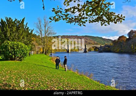 Una splendida vista autunnale del fiume Tay a Dunkeld, dove passa sotto il vecchio ponte in pietra progettato da Thomas Telford e costruito 1804-1809. Foto Stock