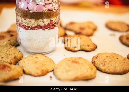 Ingrediance per il biscotto in contenitore di vetro e biscotti al lampone appena sfornati sul tavolo Foto Stock