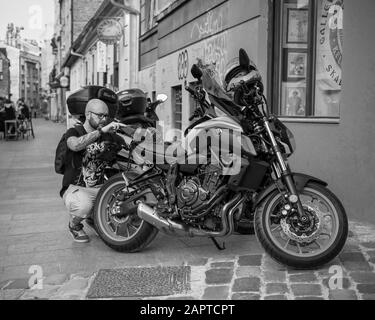 Belgrado, Serbia Luglio 5th 2019: Scena urbana con un uomo che si prepara per un giro in moto (bianco e nero) Foto Stock